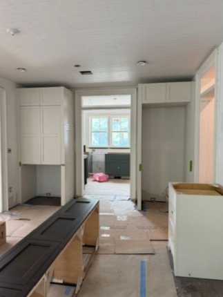 Kitchen under renovation with cabinets, countertops, and floor protection in progress.