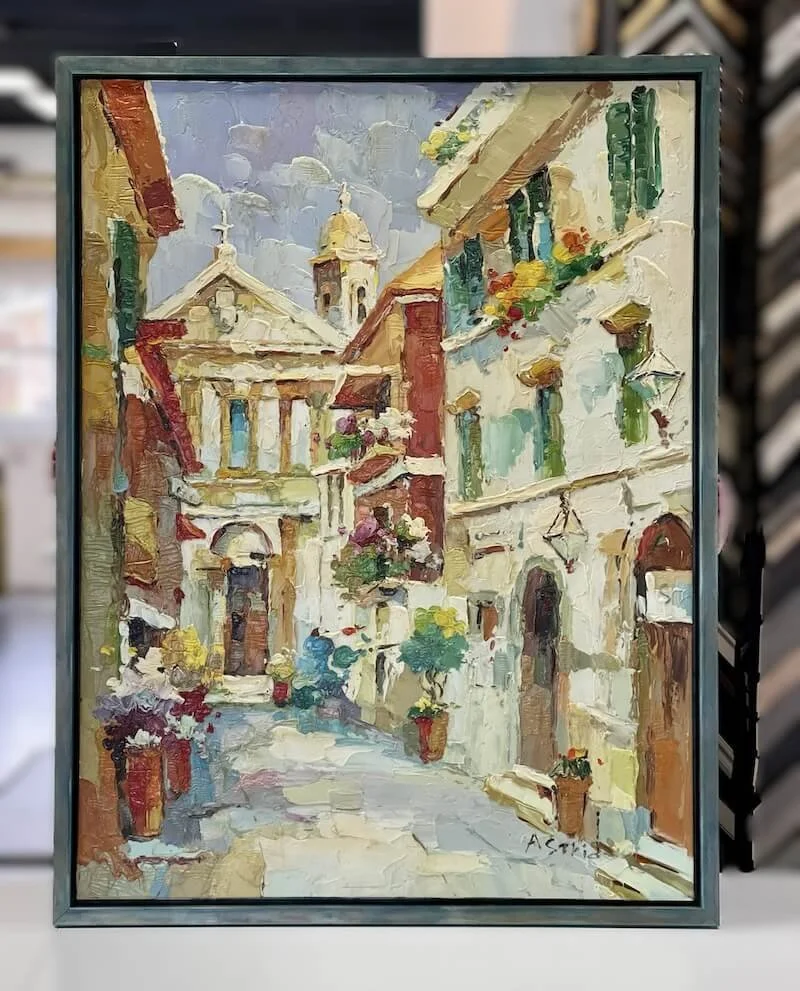 Oil painting of a narrow European street with historic buildings, potted plants, and flowers.