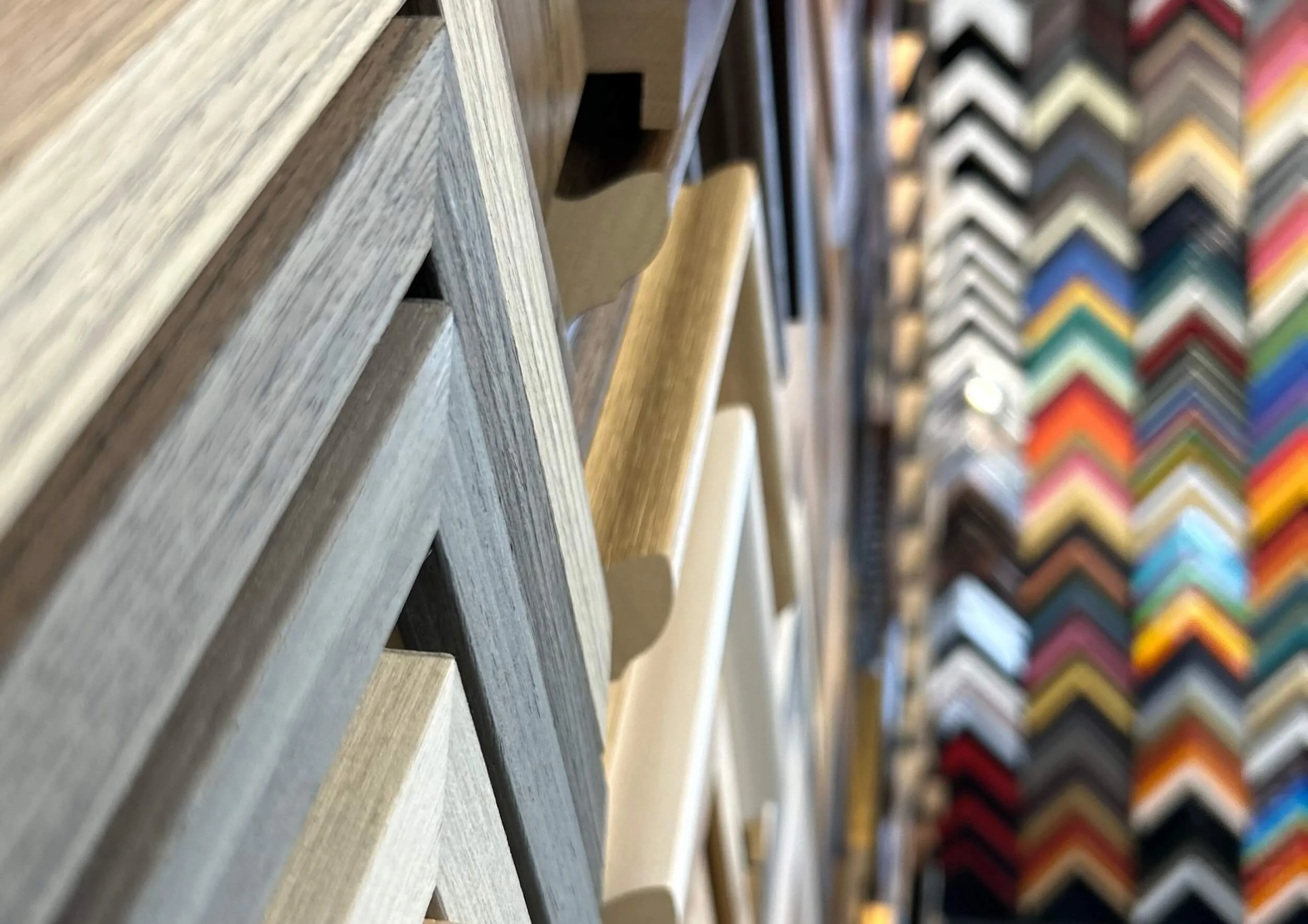 Close-up of wooden picture frame samples in various colors and finishes, arranged in a display.