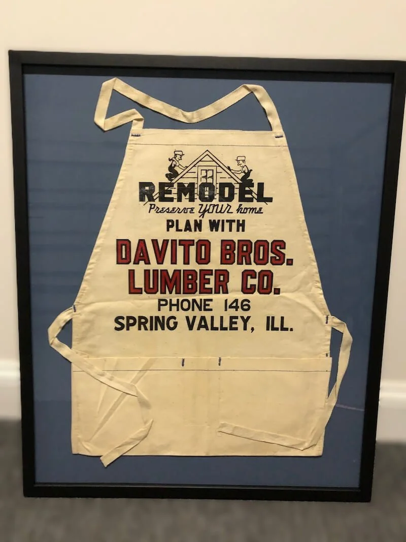 Framed vintage advertising apron for Davito Bros. Lumber Co., located in Spring Valley, Illinois, promoting remodeling and home planning services.
