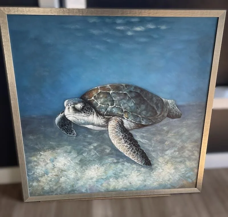 Painting of a sea turtle swimming underwater with a blue background