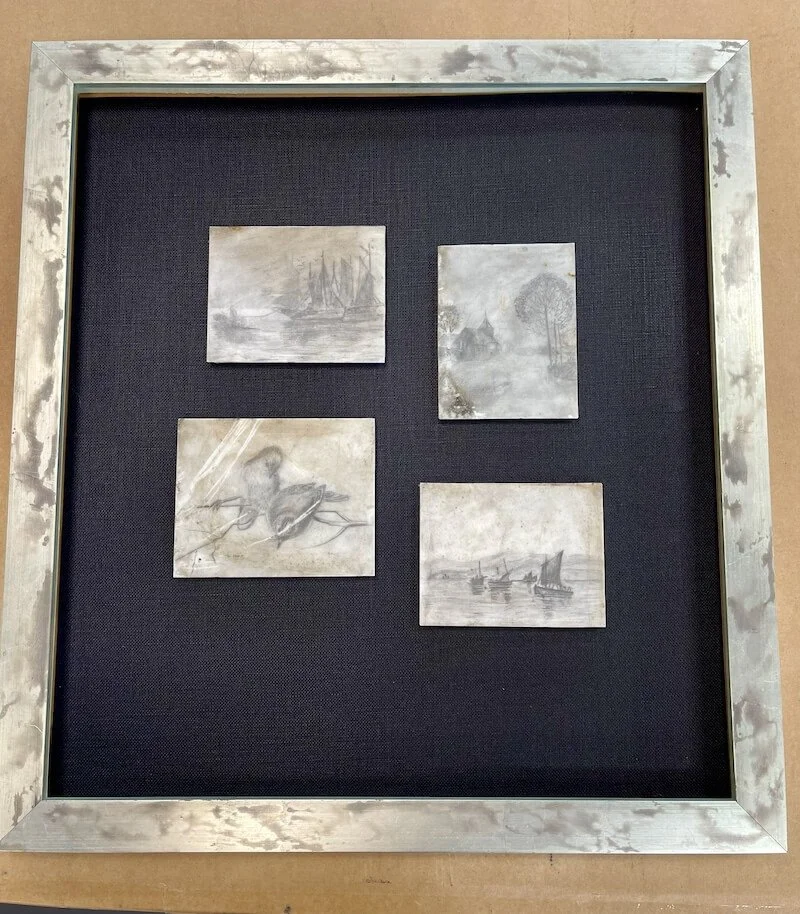 Four small weathered metal art pieces arranged in a square within a silver frame on a black background, depicting nautical scenes, trees, and boats.