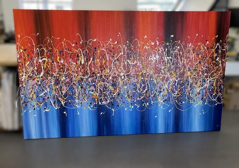Abstract painting with a red to blue gradient background and multicolored paint splatters and drips.