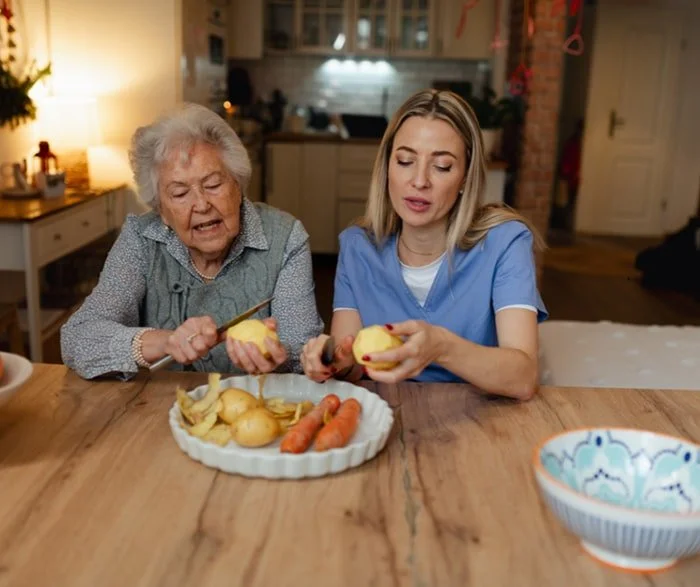 Elderly woman peeling vegetables with caregiver - companionship for aging adults