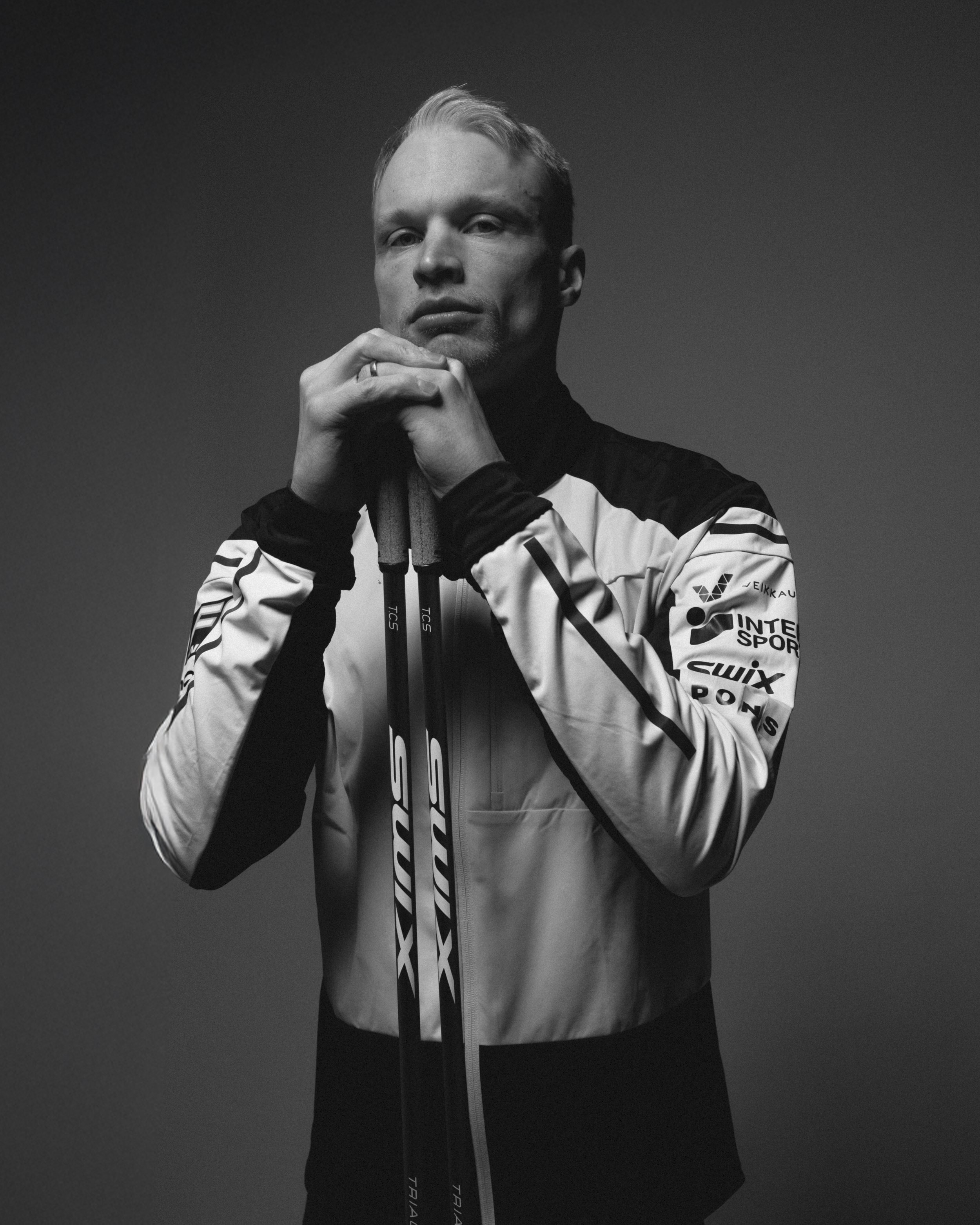 Livo Niskanen black and white portrait of a man in a sports jacket holding a pair of skis.