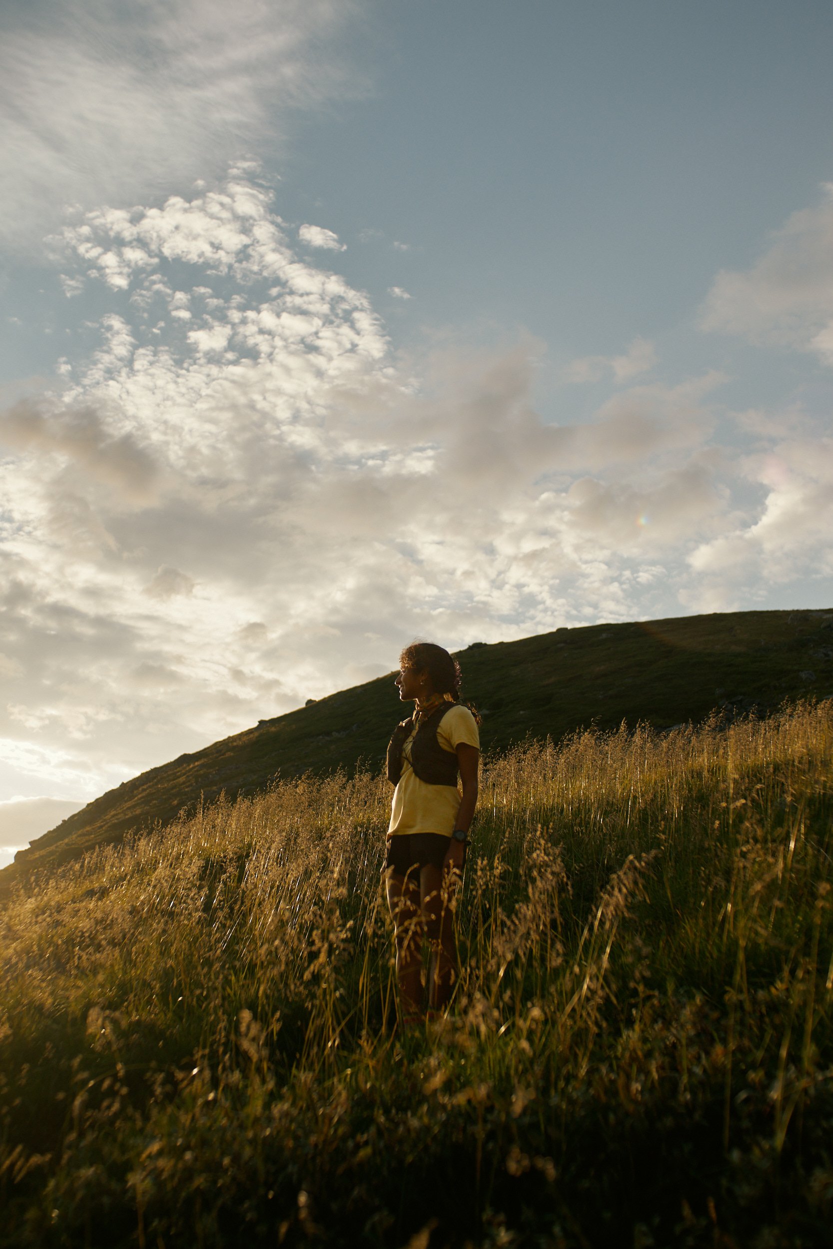 Shanga Ba standing in a grassy hillside under a cloudy sky during sunset.