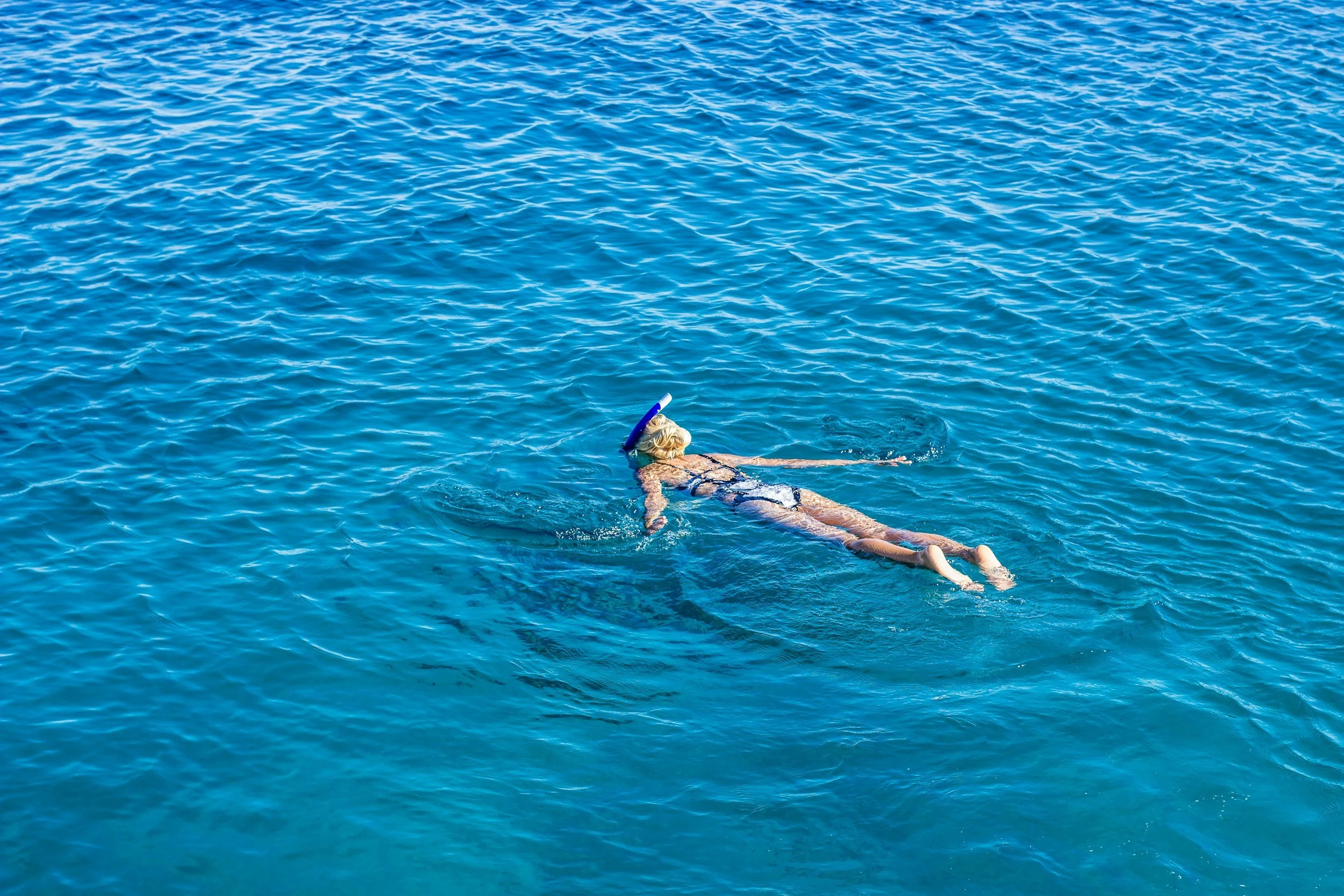 Person swimming in the open ocean with a snorkeling mask.