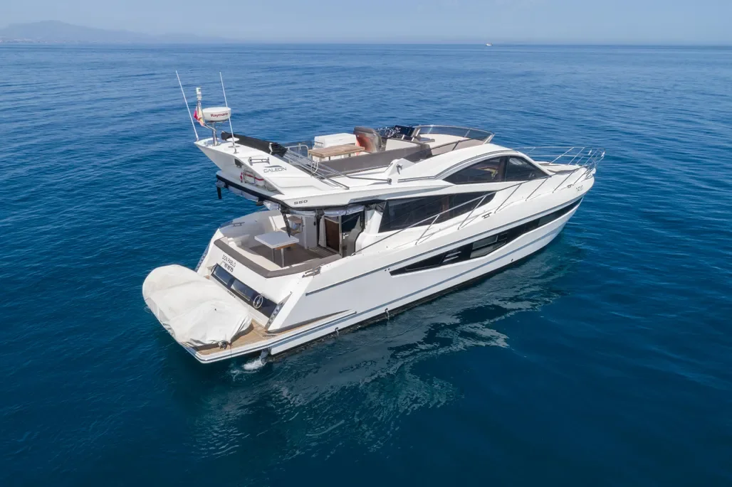 A white yacht with multiple decks floating on calm blue ocean water.