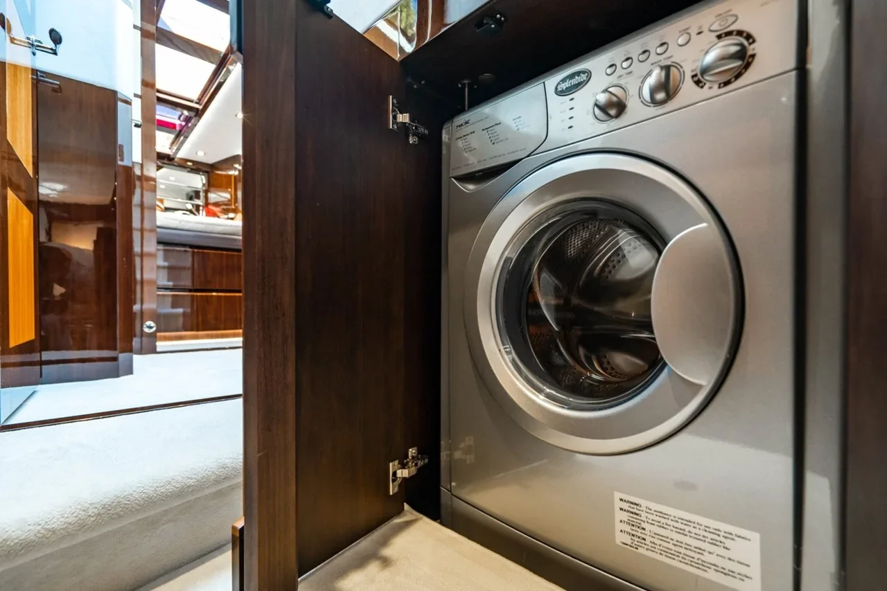 A front-loading washing machine inside a wooden cabinet space