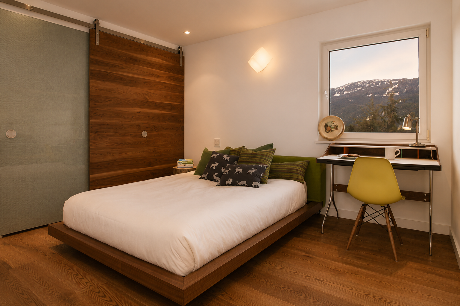 A cozy bedroom with a bed that has pillows featuring dog and striped patterns, a wooden headboard, a desk with a yellow chair, a window showing mountains and trees, and warm lighting.