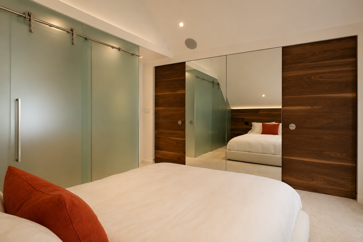 Modern bedroom with a large bed, white bedding, orange pillows, mirrored closet doors, and wood-paneled walls