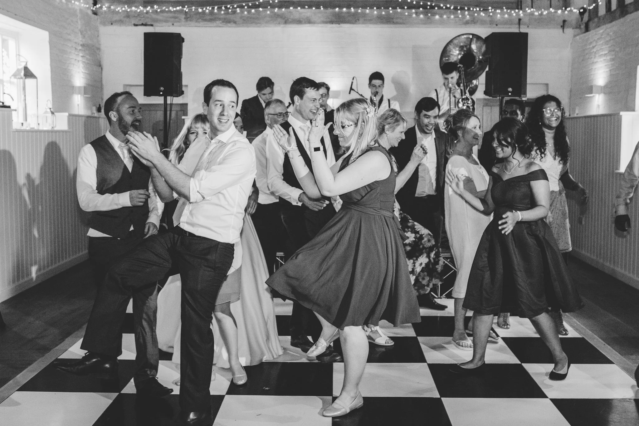 People dancing and enjoying themselves on a checkered dance floor in a celebration or party setting.