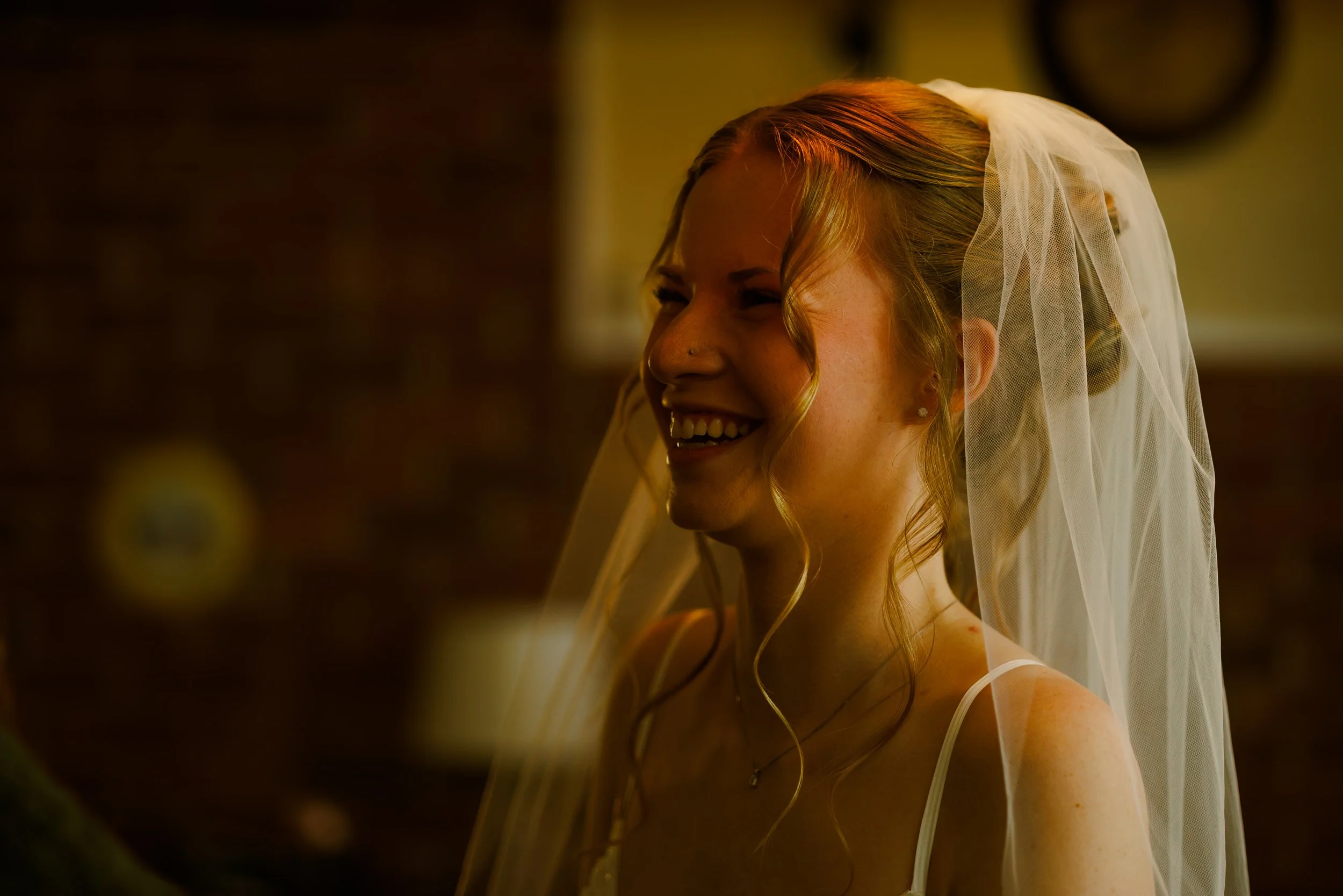A woman with red hair, wearing a bridal veil, smiling in a close-up shot.