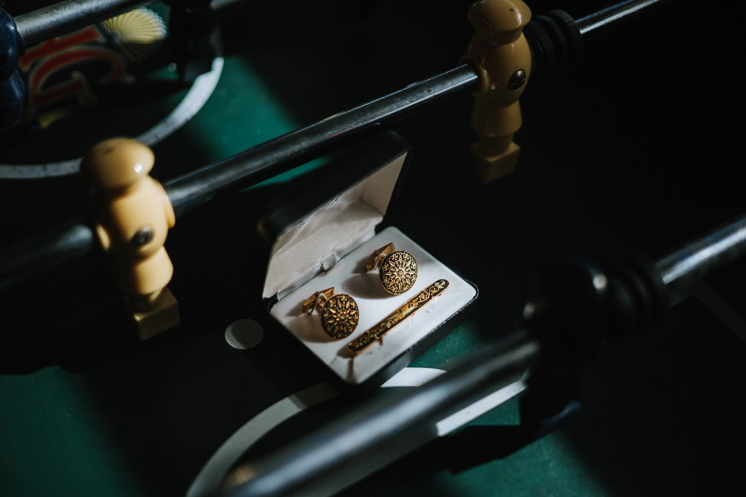 Gold jewelry, including earrings and a collar, displayed inside a white jewelry box, placed on a dark tabletop.