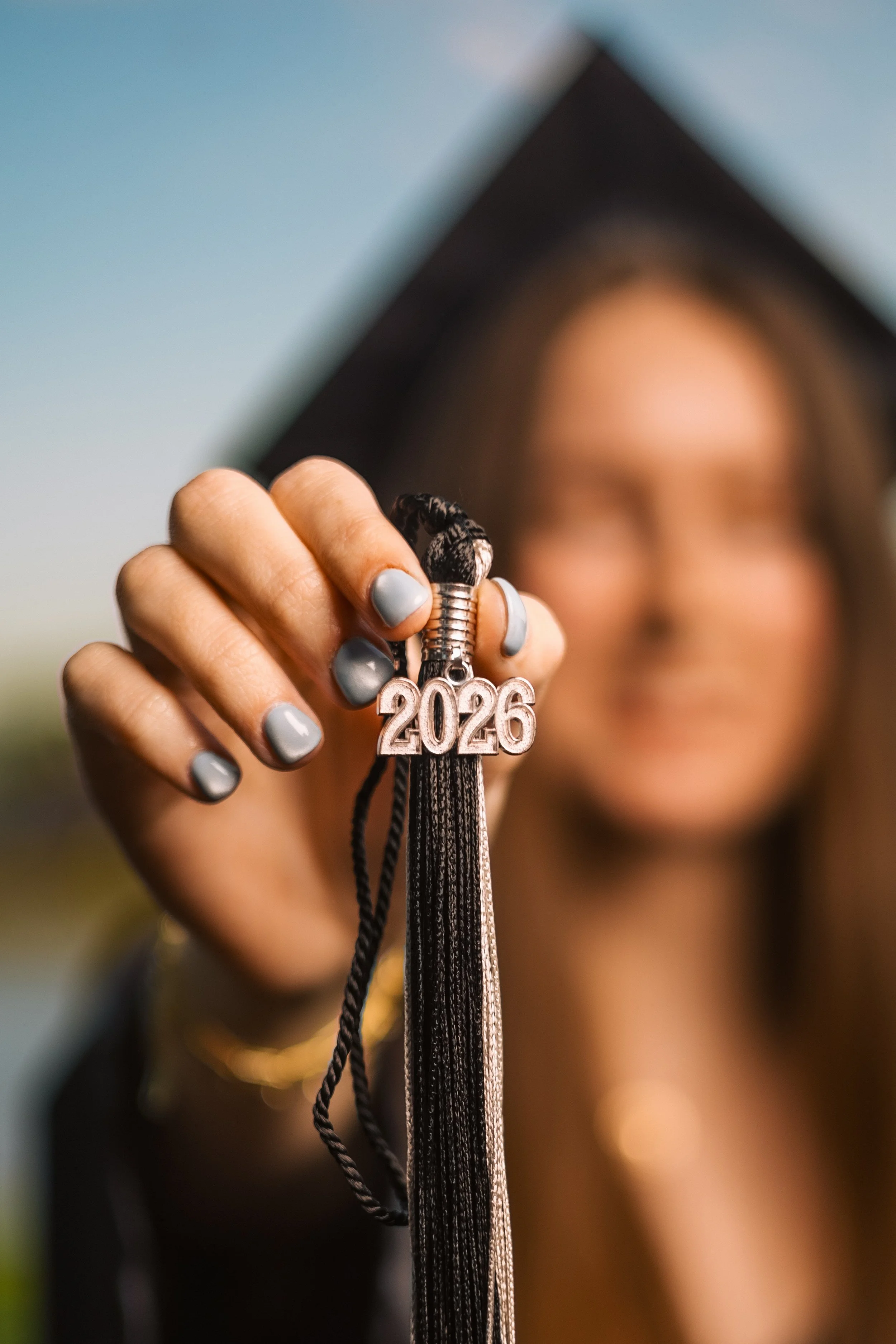 A person wearing a graduation cap holding a keychain with the year "2026" in metallic letters.