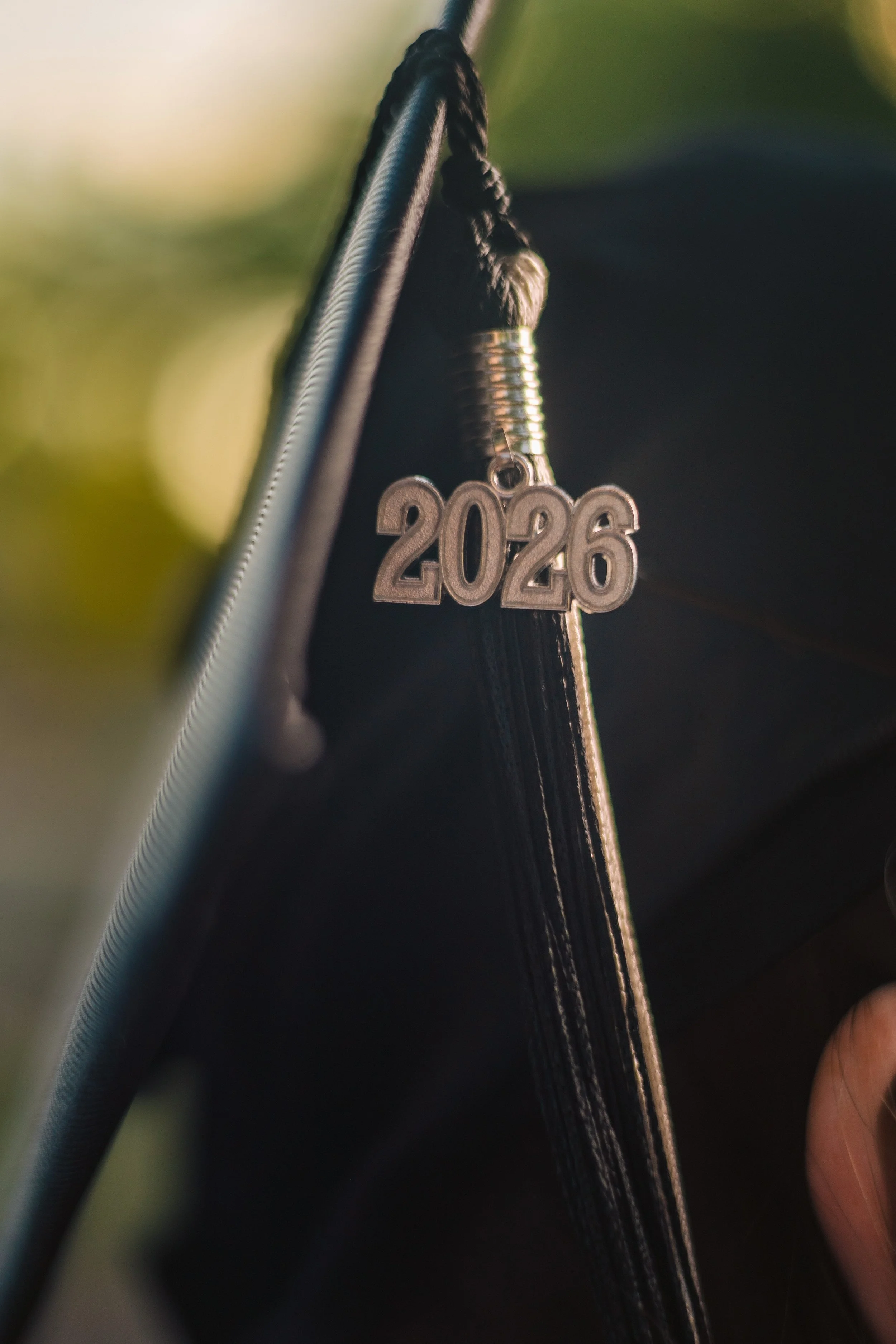 A close-up of a zipper on a black fabric item, with a keychain hanging from it featuring the numbers '2026'.