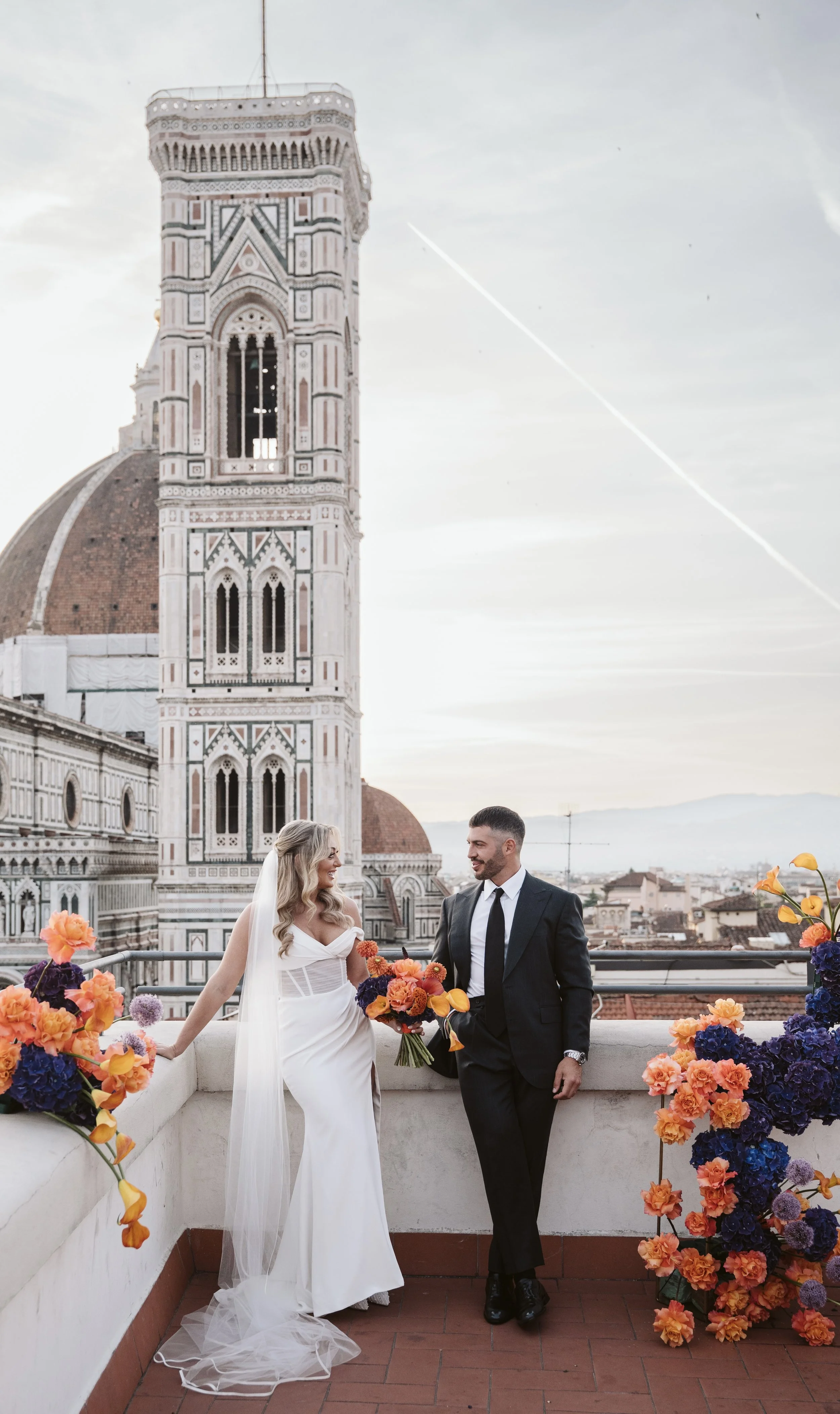 Una coppia di sposi su un terrazzo con vista sul Duomo di Firenze, decorato con fiori colorati.