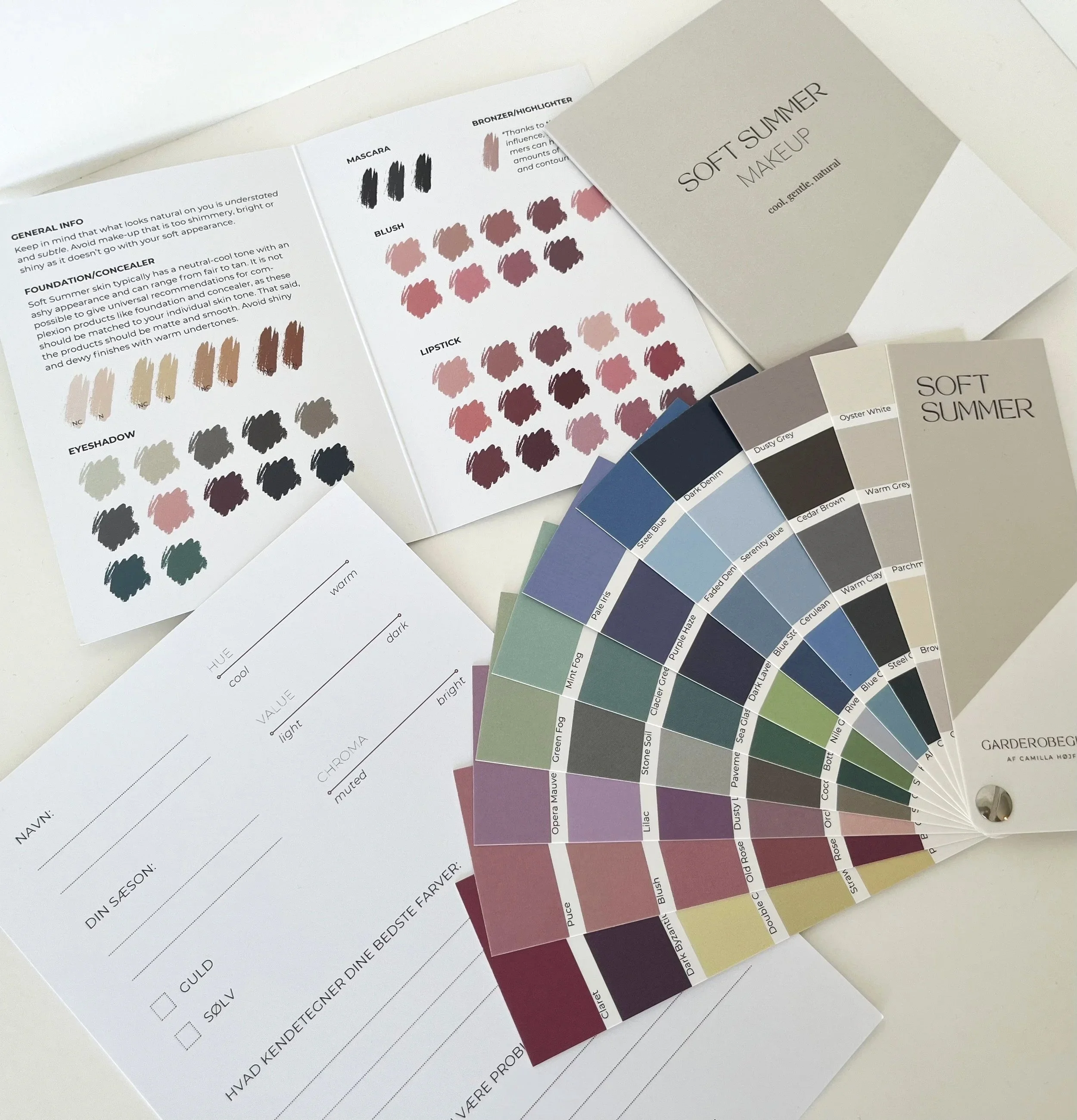 Billede af farvekort med forskellige nuancer og navne til tøjvalg, inklusive farvekoder og navne som Dusty Grey, Ocean White, Steel Blue, og Pale Iris, samt information om makeup- og hudtoner.