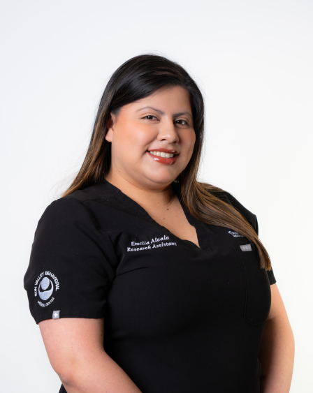 Woman with dark hair wearing a black uniform with research assistant badge, smiling against a plain white background.