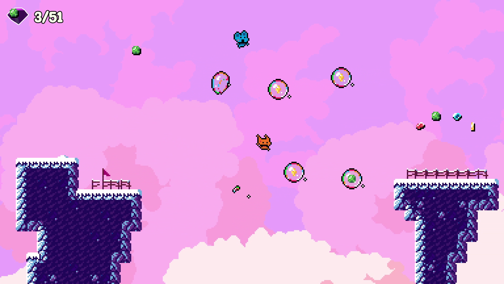 A pixel art video game scene with a pink cloudy sky background. A small brown cat is flying or jumping through the air among colorful bubbles and orbs. There are dark blue icy platforms with fences at the bottom and top left and right corners.