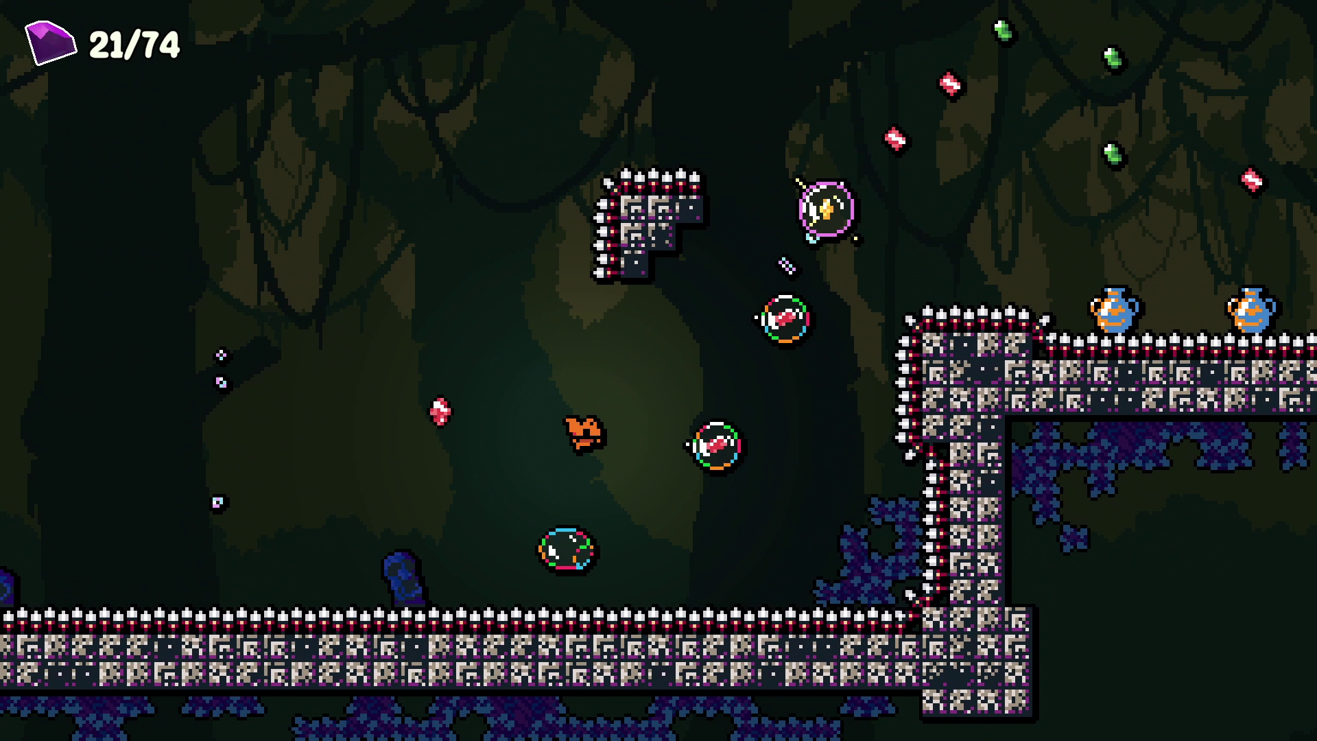Screenshot from a pixel art video game showing a dark, forest-like background with various creatures and objects, including a small animated character, spikes, and structures.