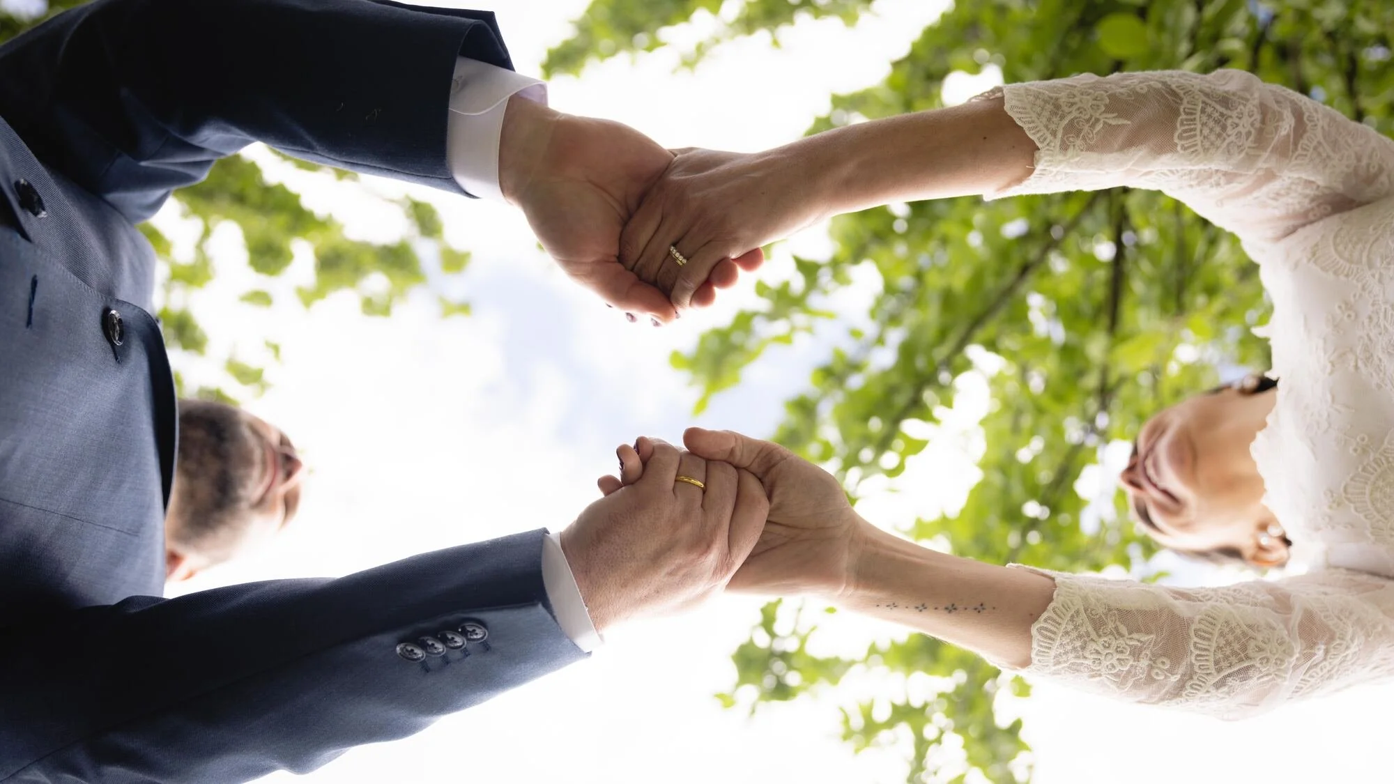 Manos de los novios unidas vistas a contrapicado bajo los árboles, boda en Chiloé	