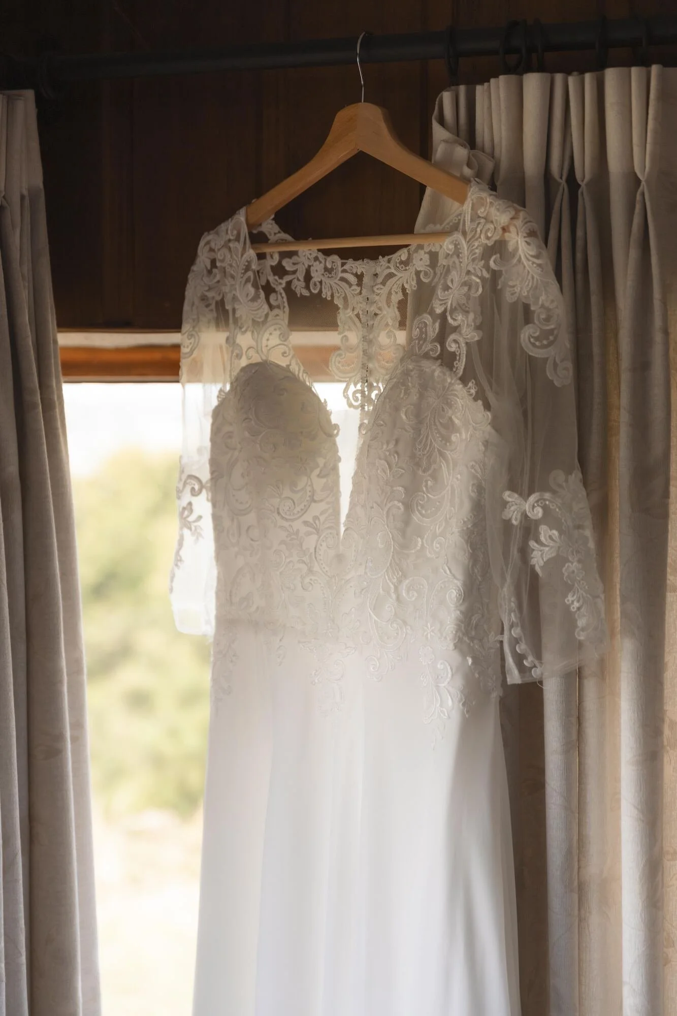 Vestido de novia de encaje colgado junto a la ventana durante los preparativos en Chiloé
