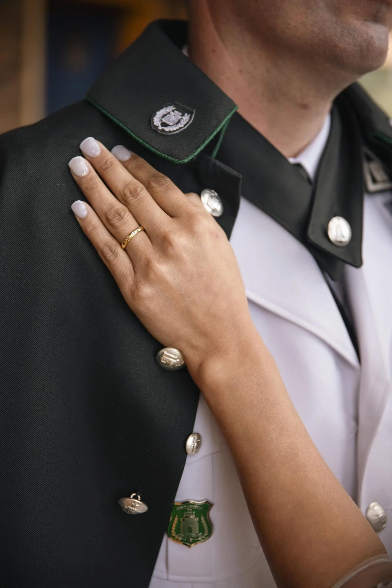 Detalle de la mano de la novia sobre el uniforme militar del novio, boda en Chiloé