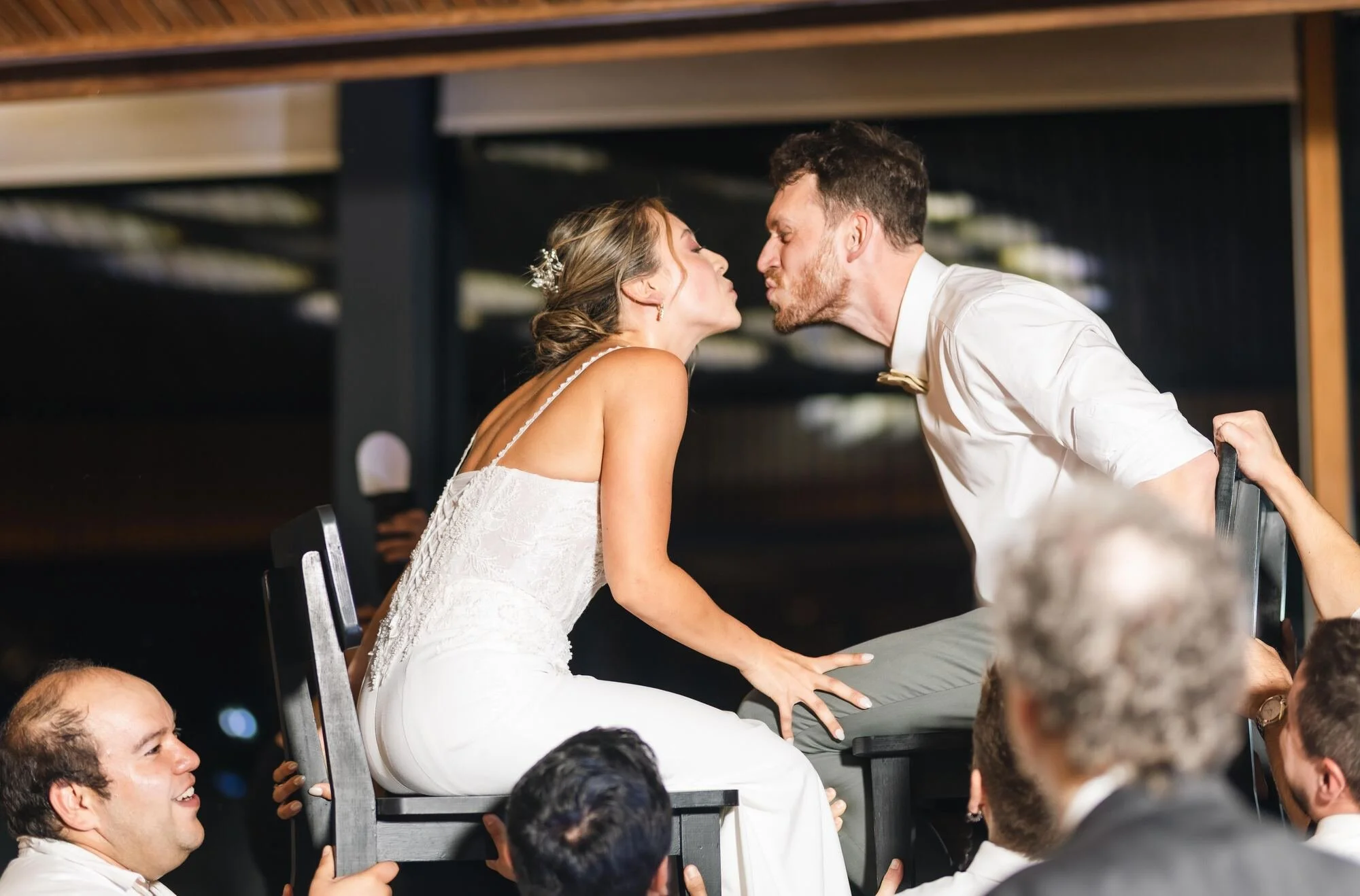 Beso de los novios mientras los levantan en andas en la fiesta, Refugia, Castro