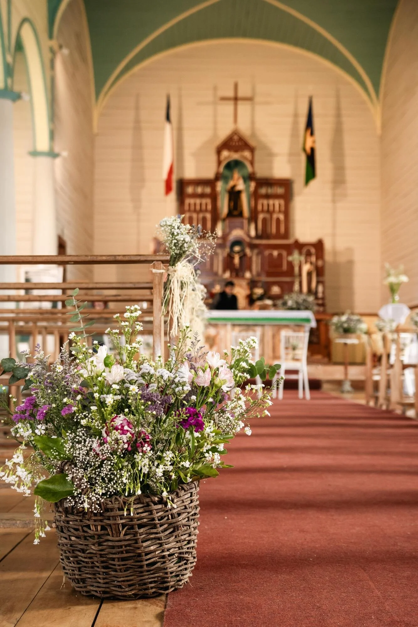 Canasto con flores silvestres decorando el pasillo de la iglesia, boda en Chiloé	