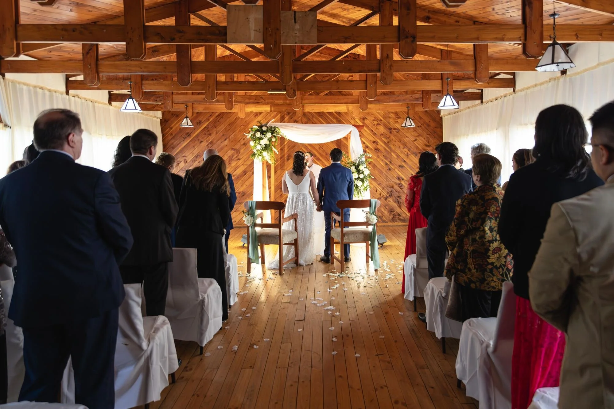 Ceremonia religiosa en un salón de madera con los invitados de pie, Castro, Chiloé	