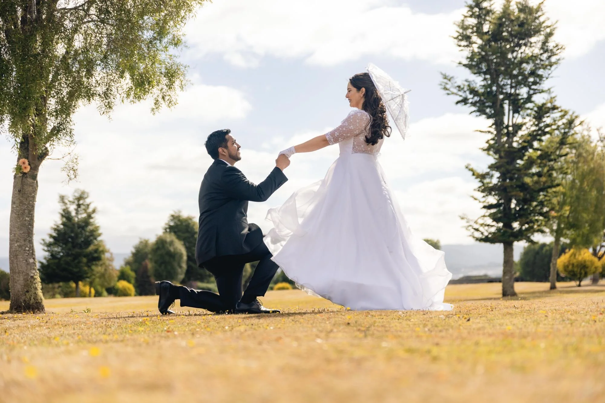 El novio de rodillas tomando la mano de la novia en el campo, Quilquico, Castro	