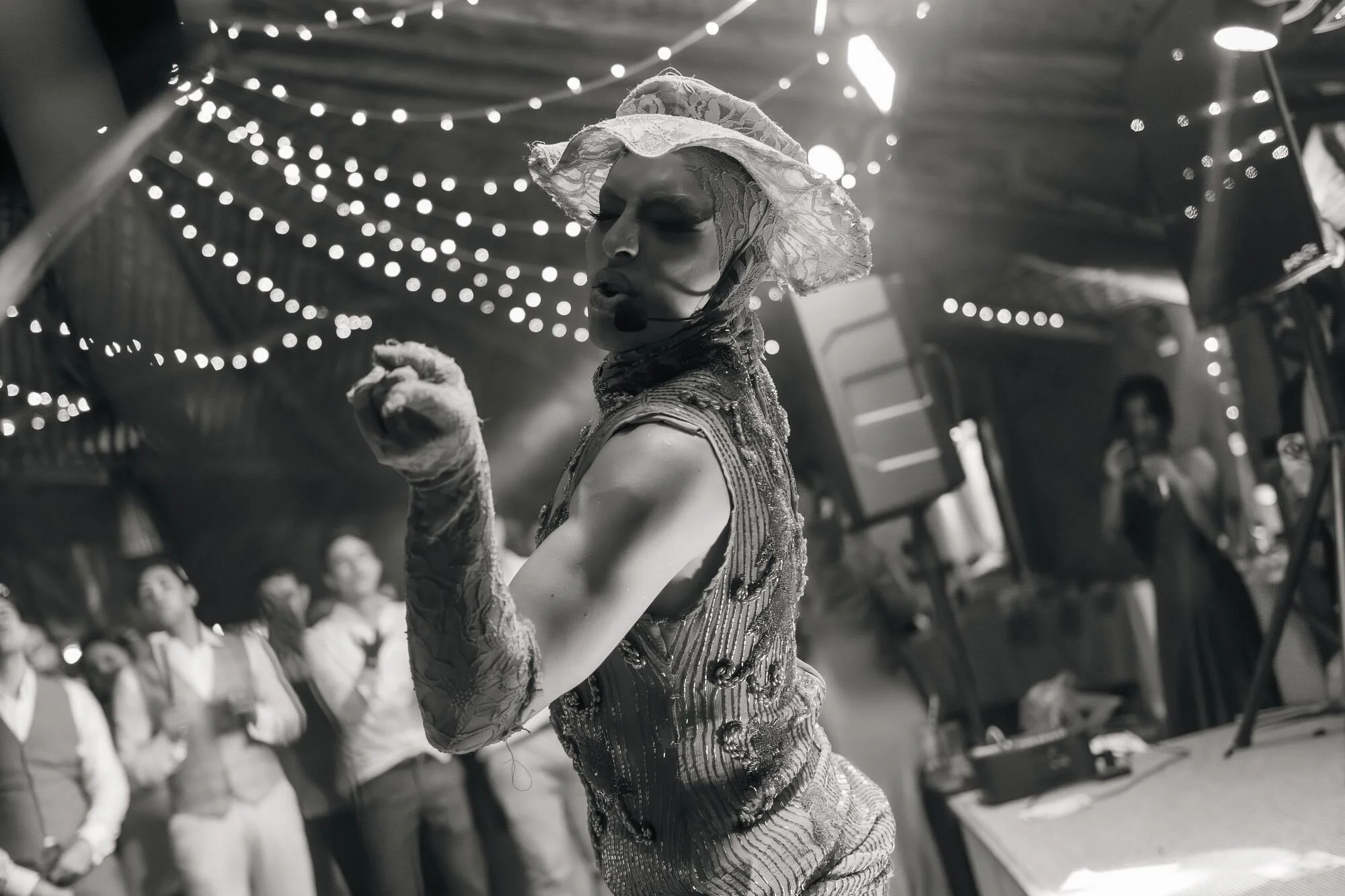 Show drag bajo las luces colgantes de la fiesta de matrimonio en Chiloé, en blanco y negro