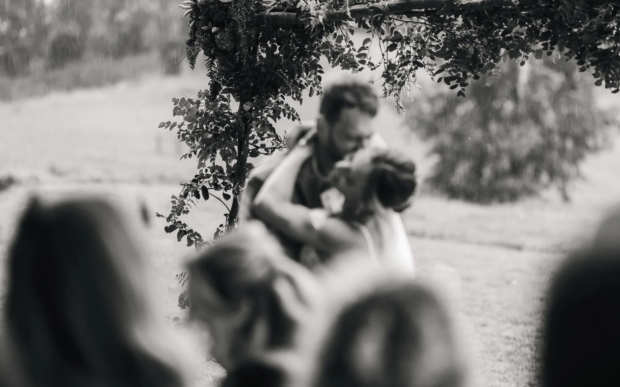 Abrazo de los novios rodeados de invitados, en blanco y negro, Refugia, Castro