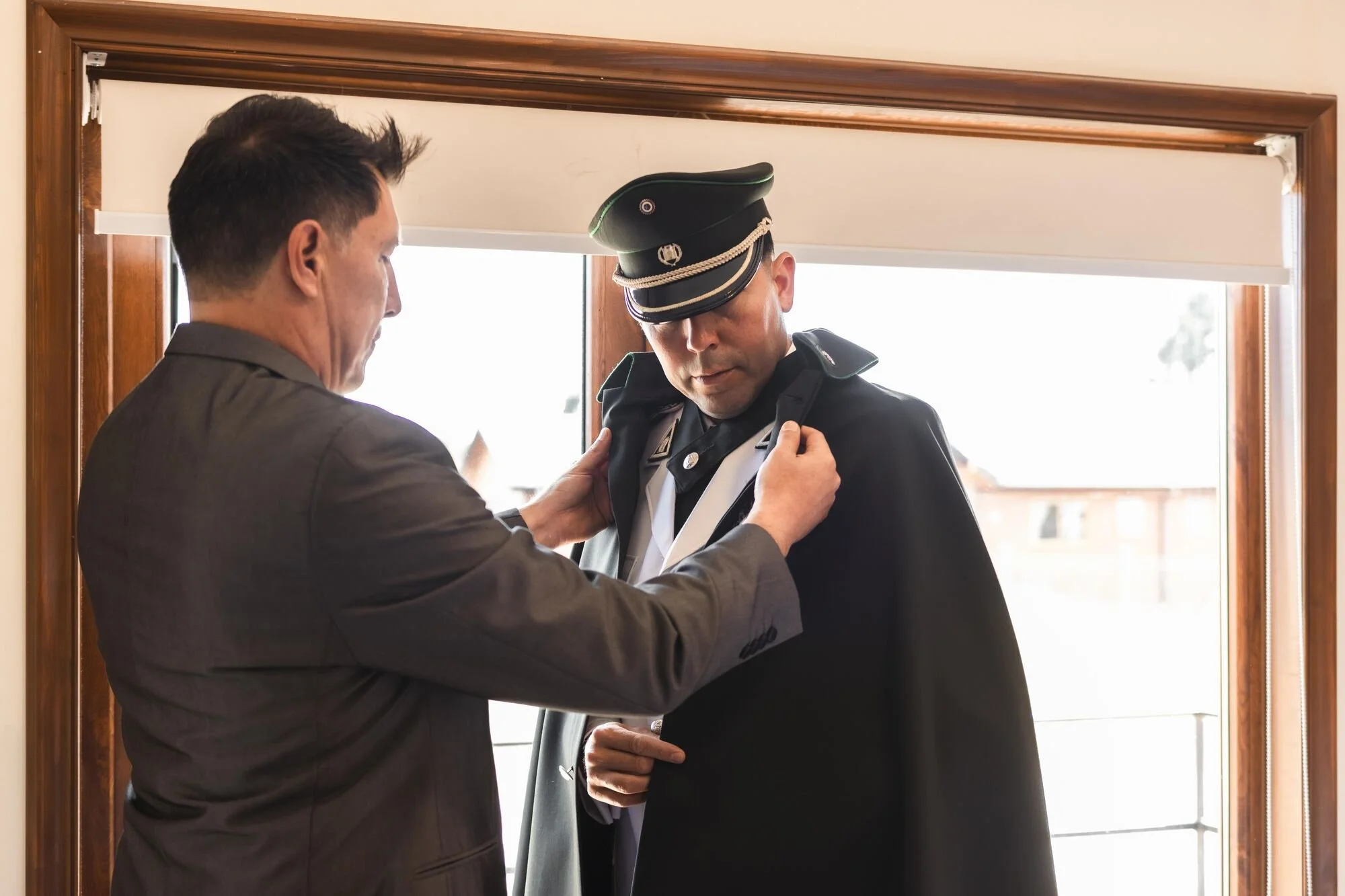 Ayudando al novio con su capa militar durante los preparativos de la boda en Chiloé