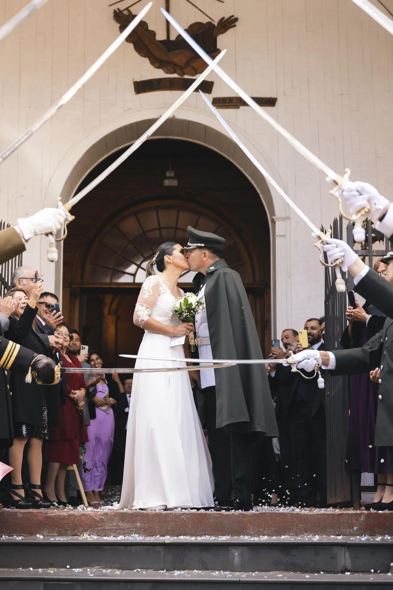 Beso de los novios bajo el arco de sables a la salida de la iglesia, boda militar en Chiloé