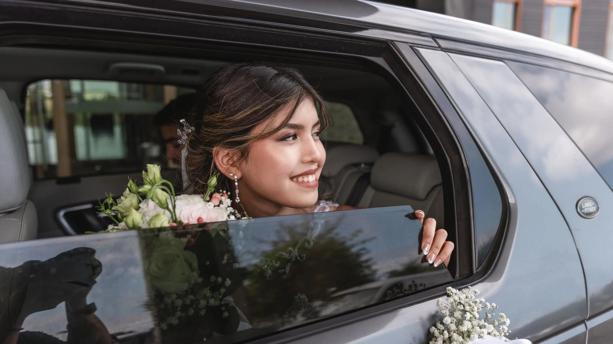 La novia asomada a la ventana del auto al llegar a la ceremonia en Castro, Chiloé	