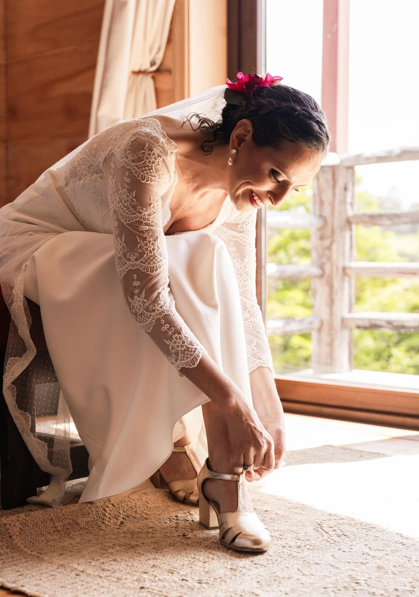 La novia poniéndose los zapatos junto a la ventana durante los preparativos en Quilquico	