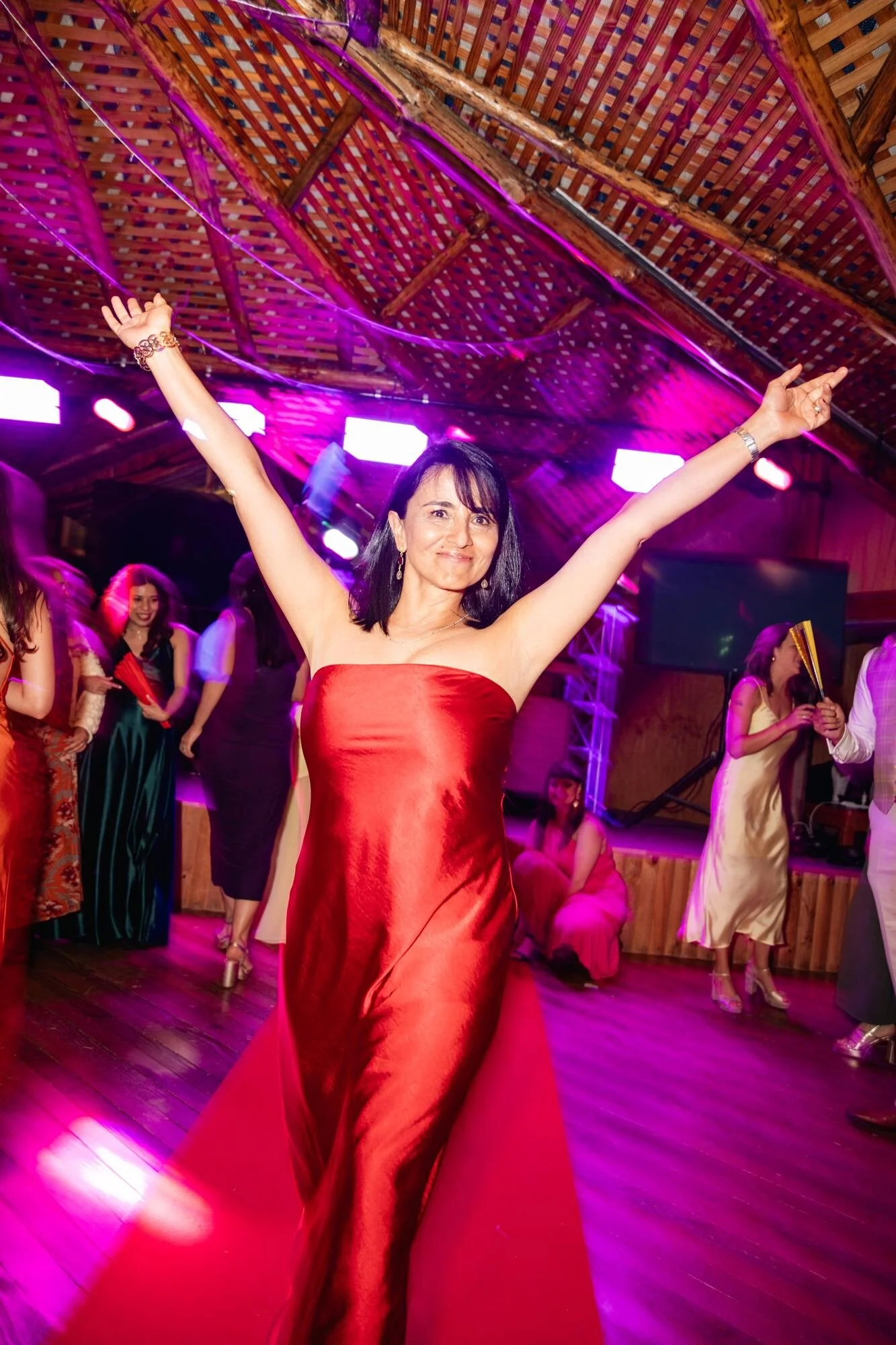 Invitada con vestido rojo bailando bajo las luces de la fiesta de boda en Ancud, Chiloé