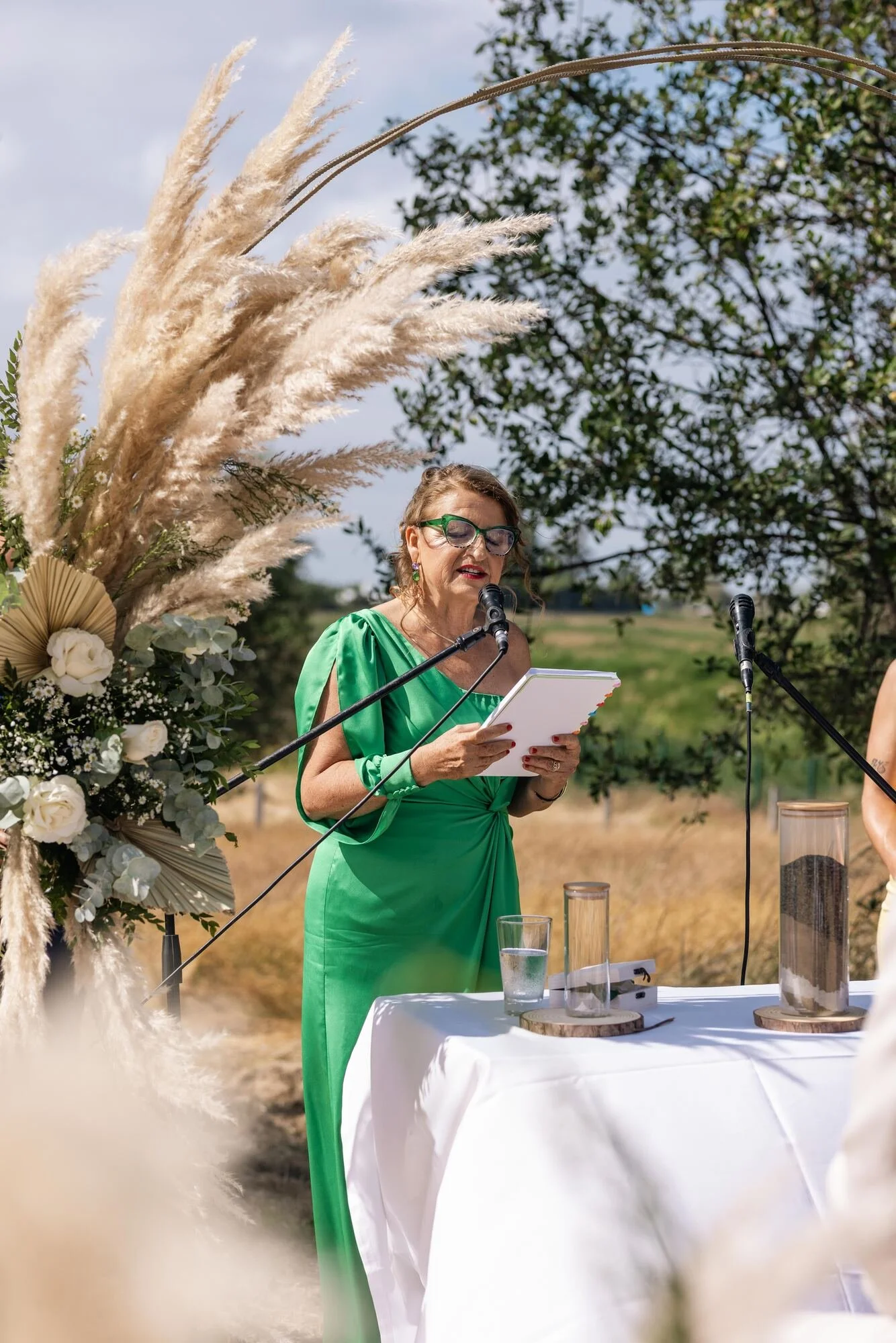 Oficiante conduciendo la ceremonia simbólica junto al arco de pampas en una boda rústica en Ancud