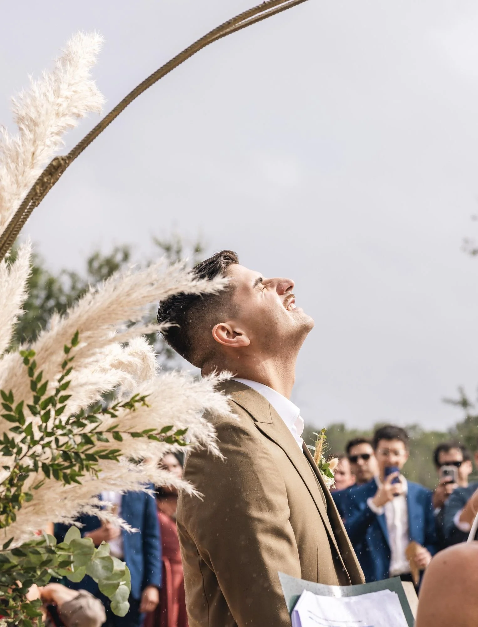 El novio bajo el arco de pampas mirando al cielo durante la ceremonia en Ancud, Chiloé