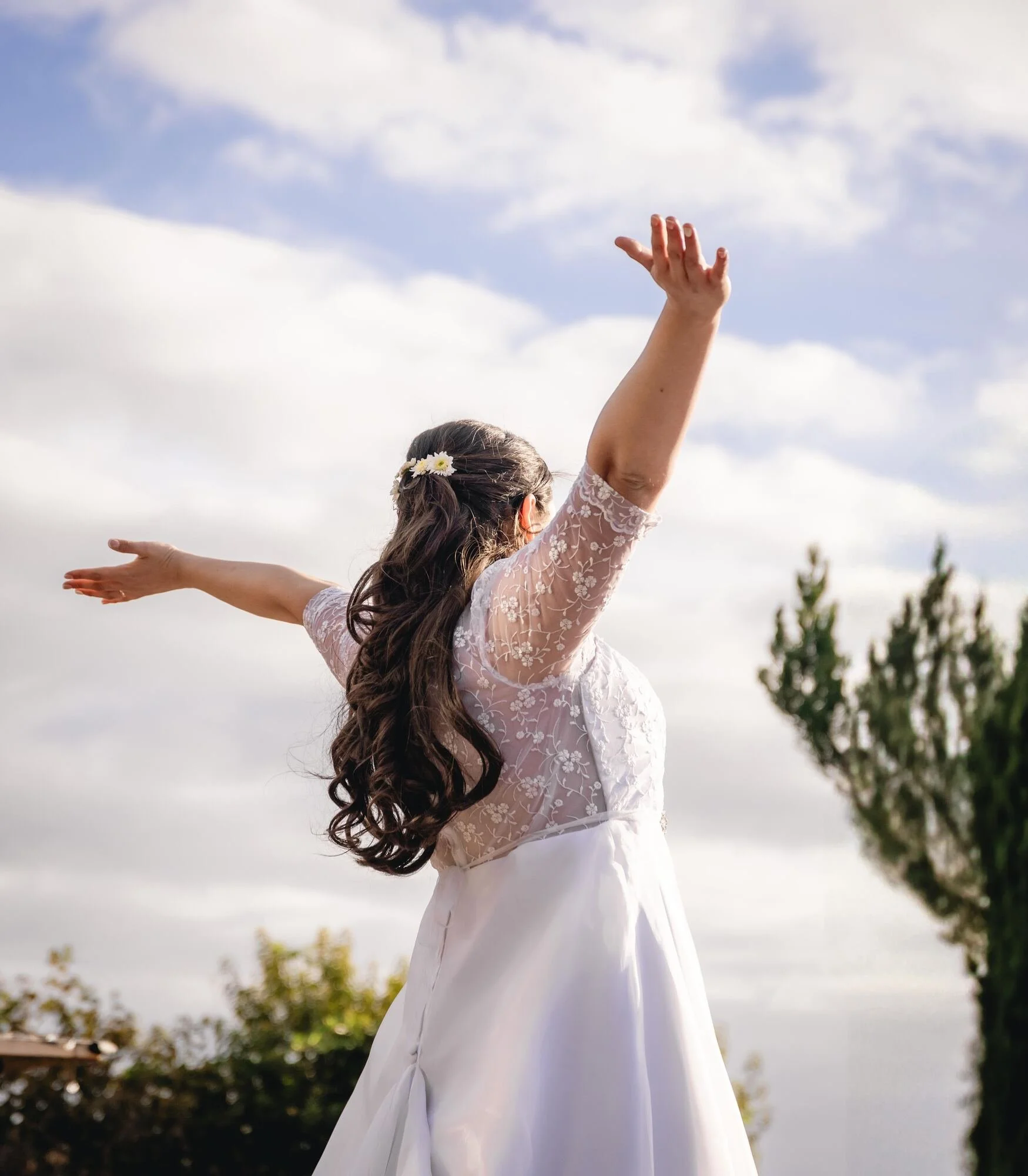 La novia girando con los brazos abiertos bajo el cielo en Quilquico, Chiloé		