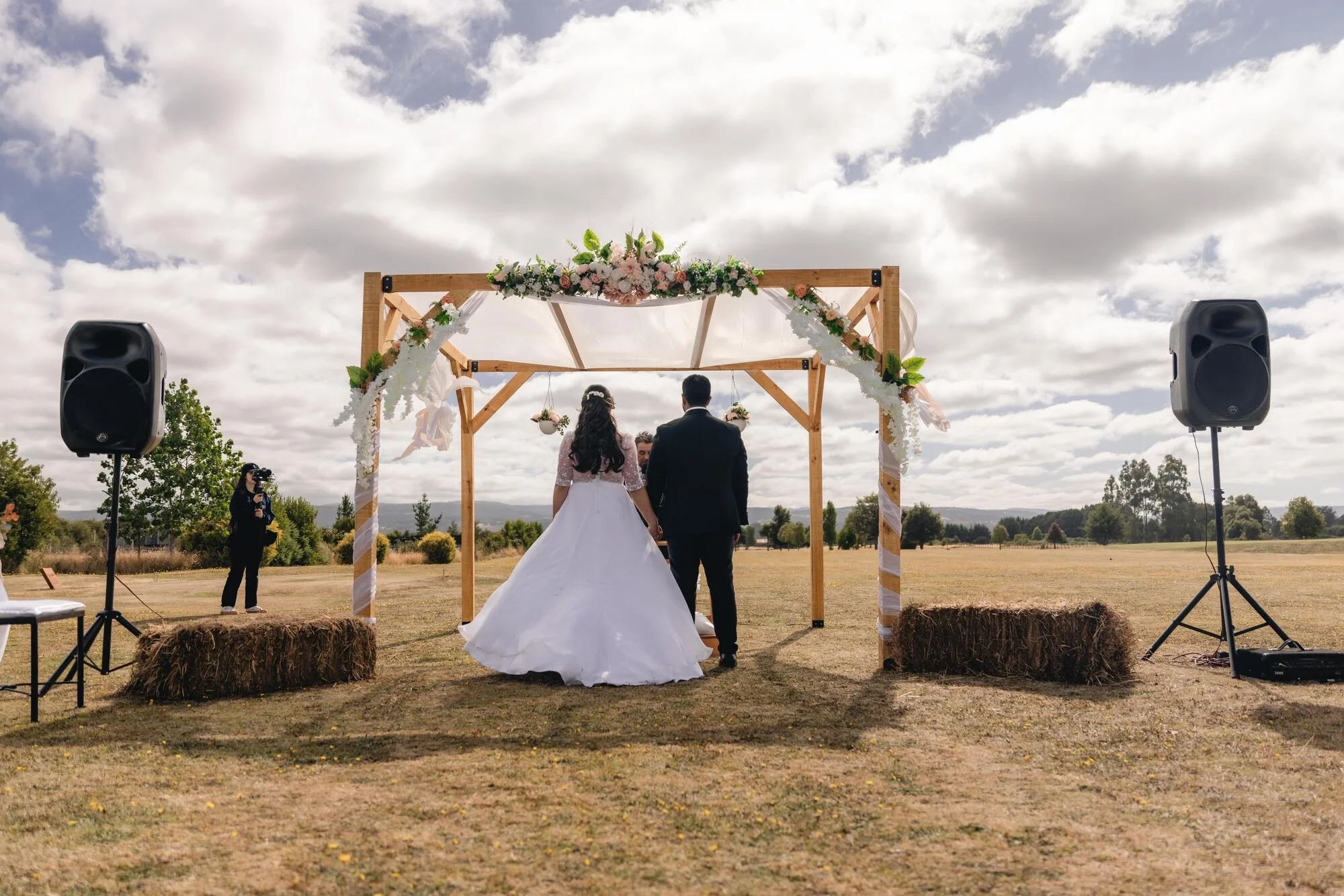 Altar con arco de madera y flores en medio del campo, boda en Quilquico, Chiloé	