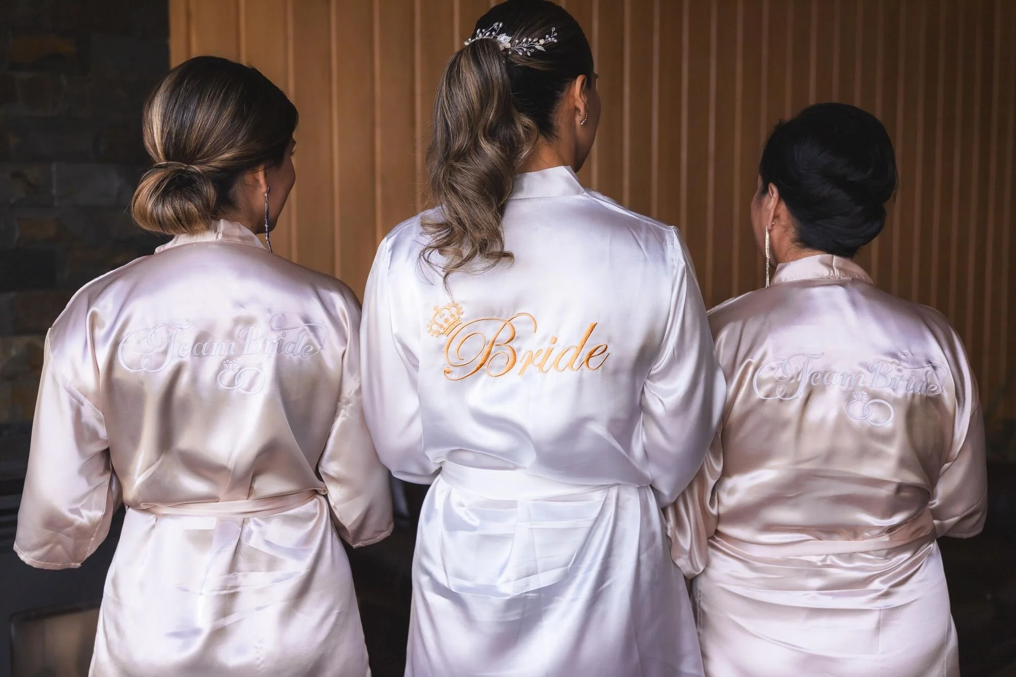 Damas de honor de espaldas con batas personalizadas antes de la ceremonia en Castro