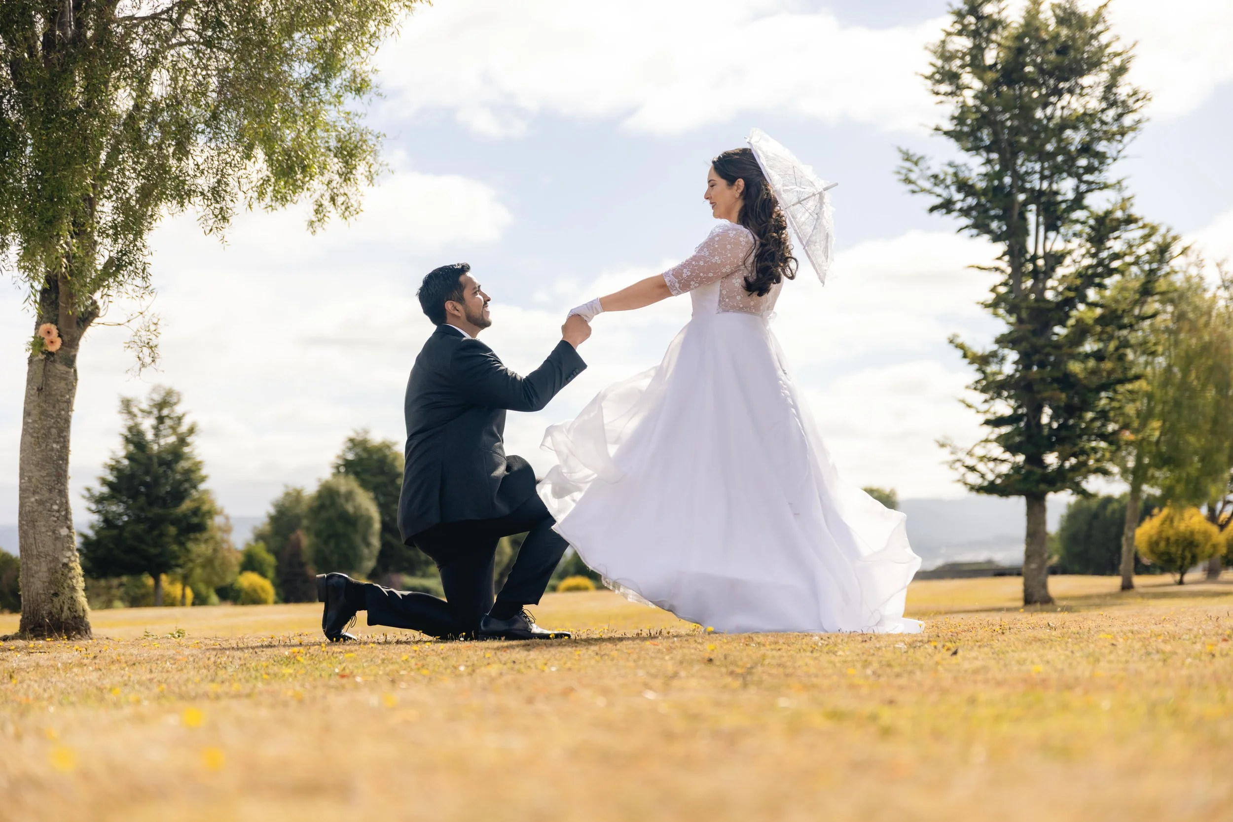 El novio de rodillas tomando la mano de la novia en el campo, Quilquico, Castro