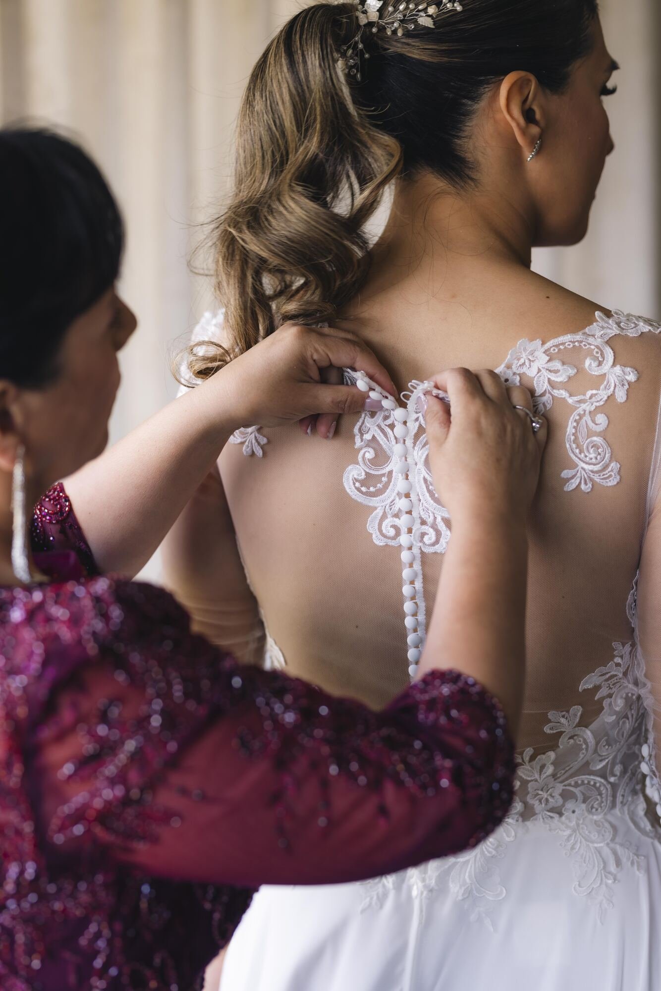 Abotonando la espalda del vestido de encaje de la novia durante los preparativos en Castro