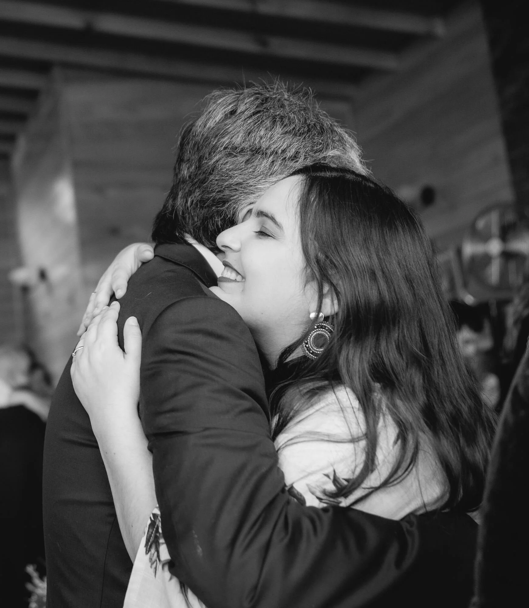 Abrazo emotivo entre invitados, en blanco y negro, matrimonio en Castro, Chiloé	