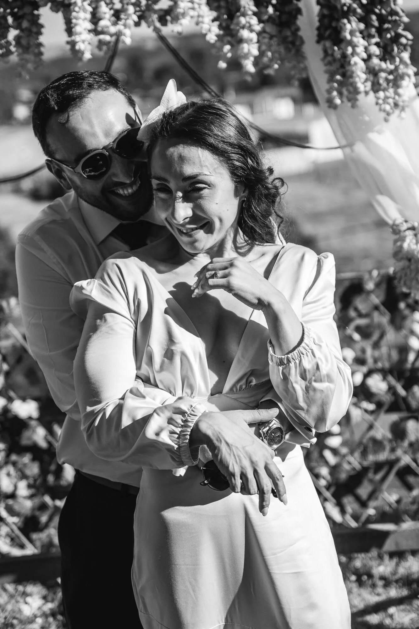 Los novios abrazados bajo el arco floral, en blanco y negro, Dalcahue, Chiloé	