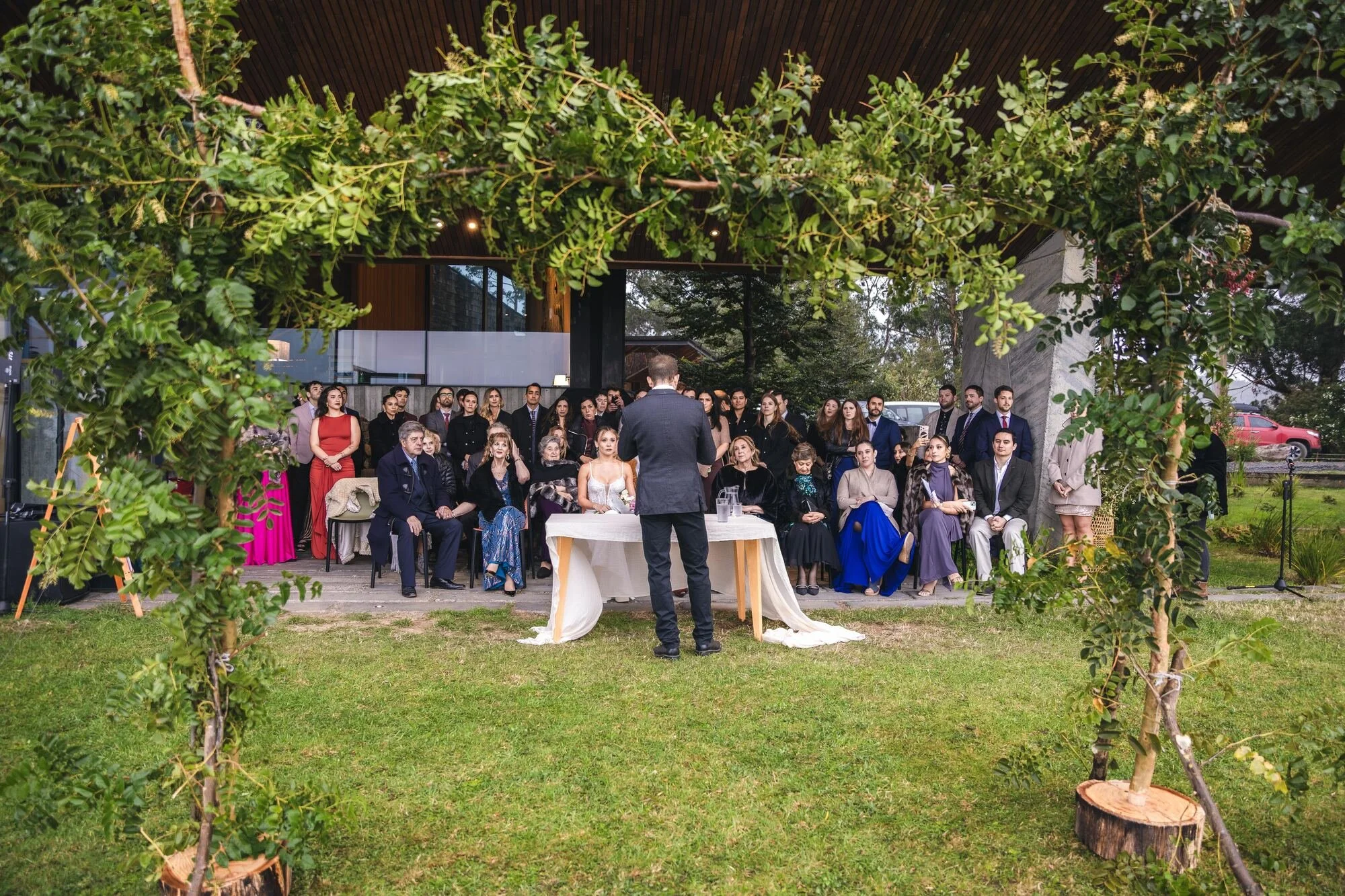 Ceremonia al aire libre bajo un arco de ramas frente a los invitados, Refugia, Castro