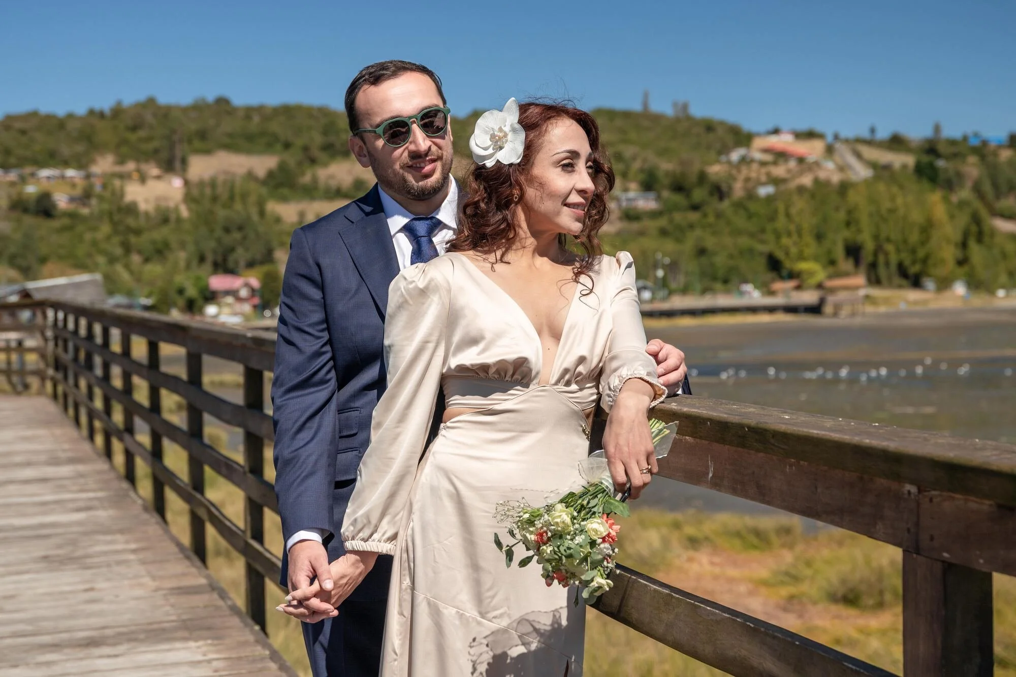 Los novios apoyados en la baranda de la pasarela con vista al humedal de Dalcahue, Chiloé	